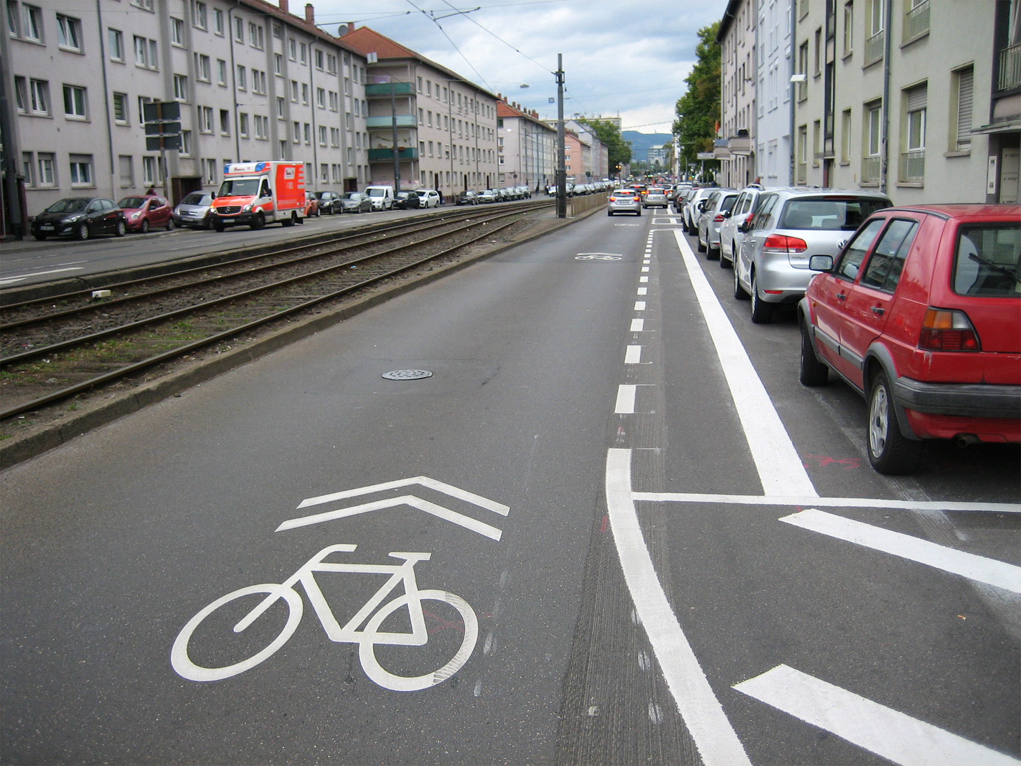 So sieht die Schloßstraße (momentan noch nur der östliche Teil) für Radfahrer*innen aus: ganz rechts Parkplätze, links daneben der Sicherheitstrennstreifen zwischen der durchgezogenen und der gestrichelten Linie, links daneben die Fahrbahn mit den Piktogrammen und SharrowsAlle Bild:Bertram Giebeler