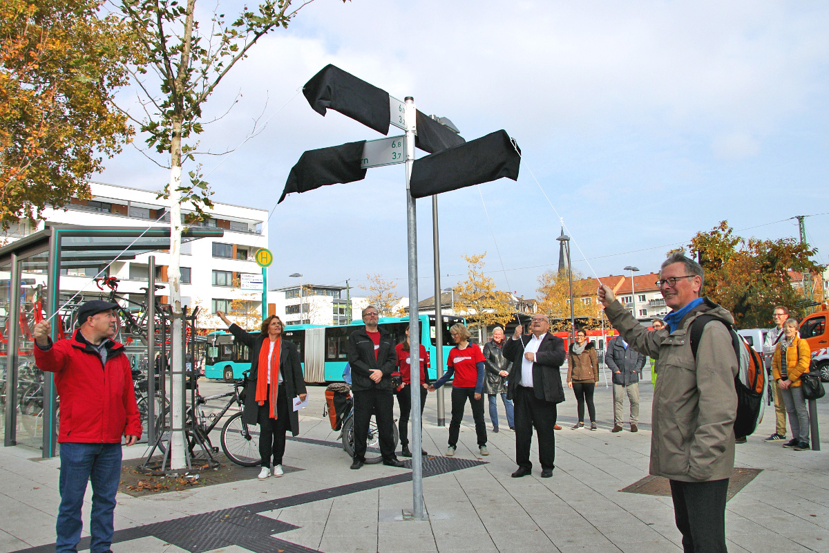 Schilder in alle 4 Richtungen an der Westseite des S-Bahnhofs Rödelheim werden "feierlich" enthüllt: von links ein Mitarbeiter des ASE – Amt für Straßenbau und Erschließung, Michaela Kraft (Leiterin des ASE), Stadtrat Klaus Oesterling, Bertram Giebeler vom ADFC Frankfurt. In den roten T-Shirts Aktive des RadentscheidsFoto: Torsten Willner