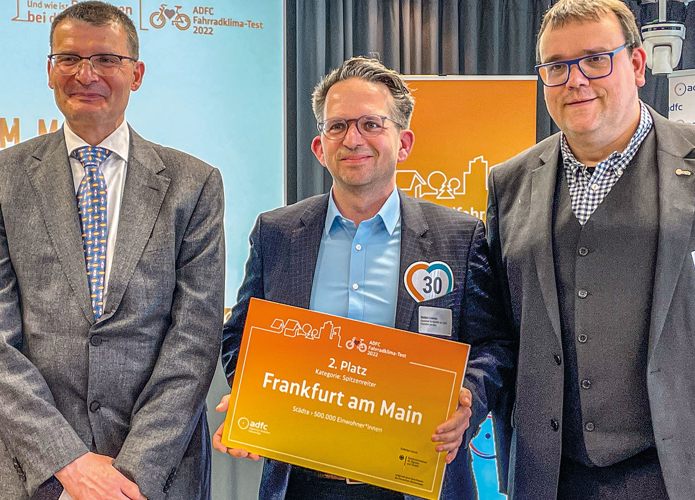 Stefan Lüdecke, Stabsstelle Radverkehr im Mobilitätsdezernat, hat die Auszeichnung Frankfurts als zweitplatzierter Stadt mit mehr als 500.000 Einwohner:innen von Staatssekretär Hartmut Höppner (links) und ADFC-Bundesvorstandsmitglied Christoph Schmidt entgegengenommen.Fahrradklima-Test