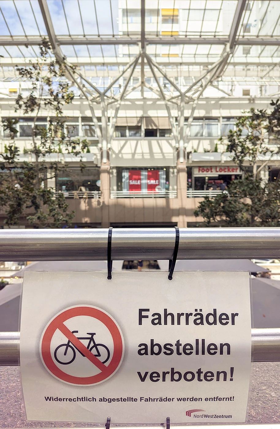 Auf dem Schild steht "Fahrräder abstellen verboten!". Im Hintergrund sieht man leerstehende Geschäfte