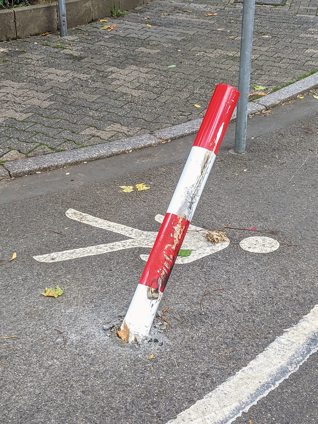 Ein Poller, der angefahren wurde, steht schief auf dem Gehweg