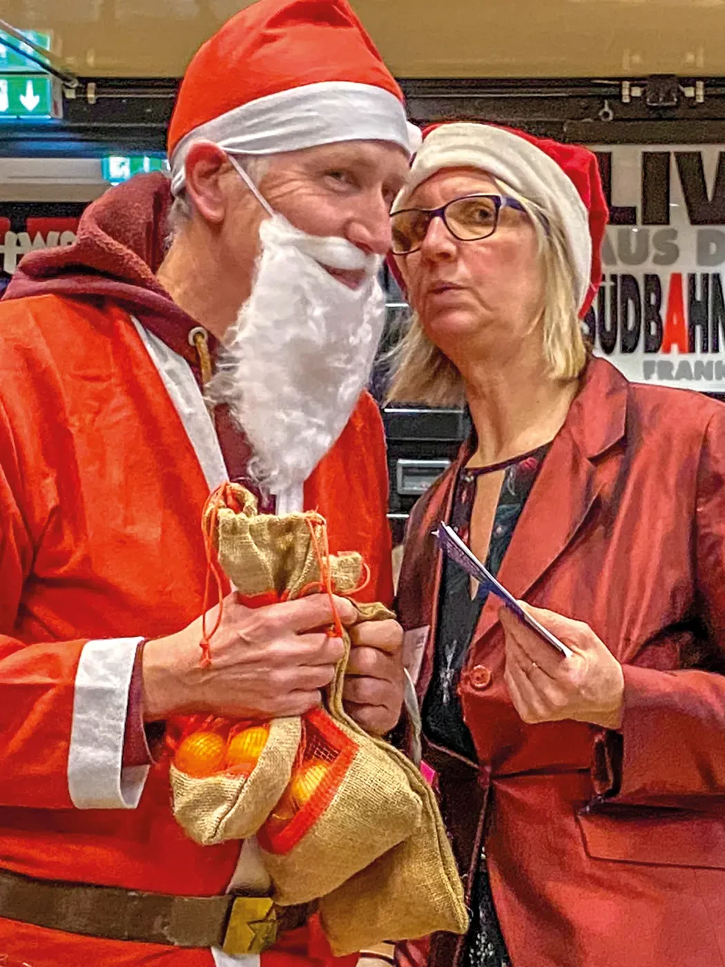 Ein Mann im Nikolauskostüm steht neben einer Frau mit einer Nikolausmütze