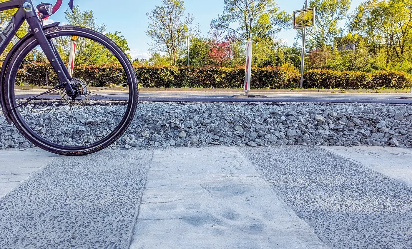 Der Höhenunterschied zwischen dem alten, niedrigen Übergang und dem neuen, erhöhten Radweg (auf dem Schotterbett dahinter) ist beachtlich. Zukünftig bleibt Radfahrenden dieses Auf und Ab (und die Fahrt über holprige Bordsteinkanten) erspart.<br><span class="image-copyright">Ansgar Hegerfeld</span>