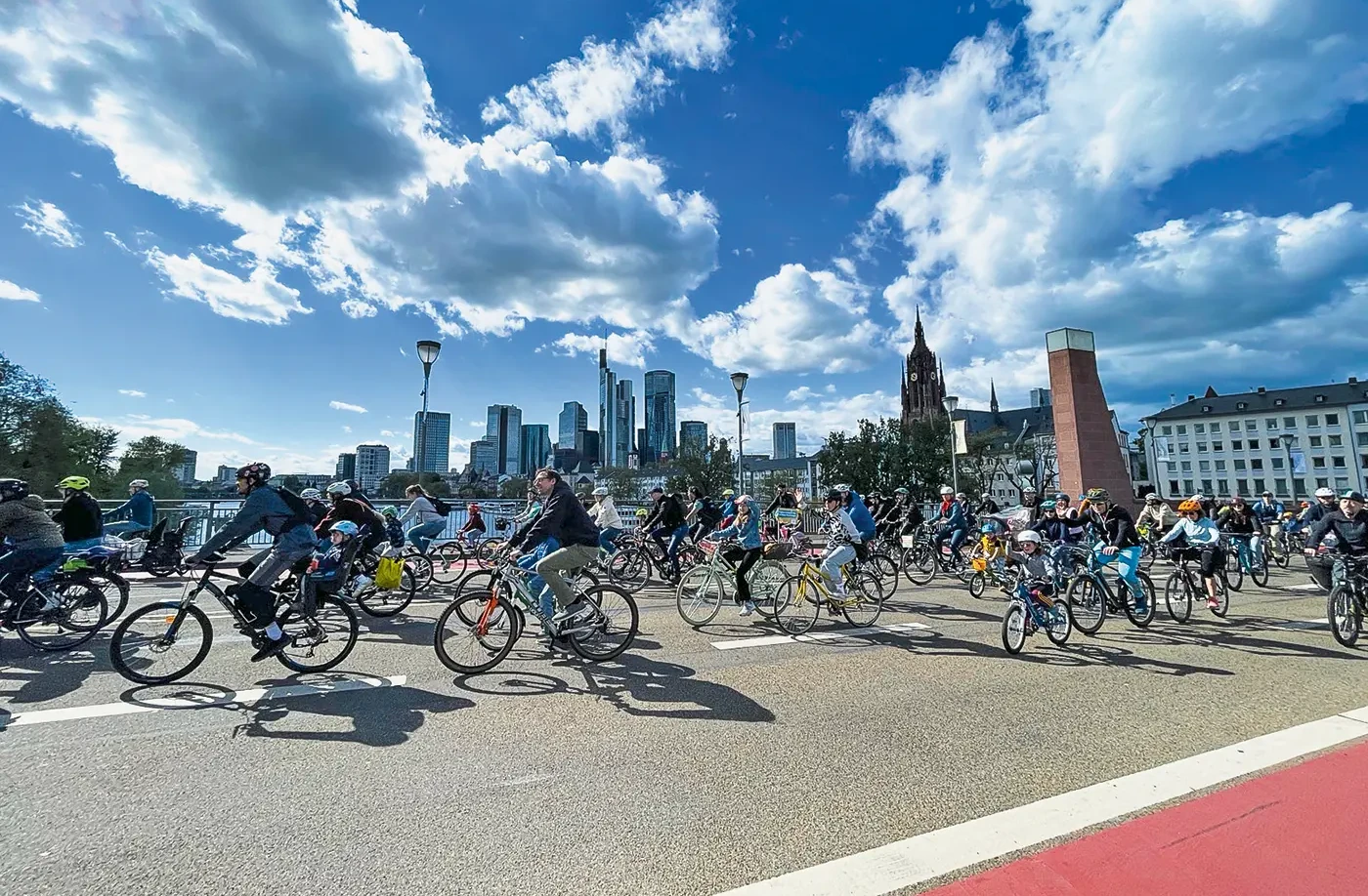 Radfahrende überqueren eine Brücke, im Hintergrund die Skyline von Frankfurt